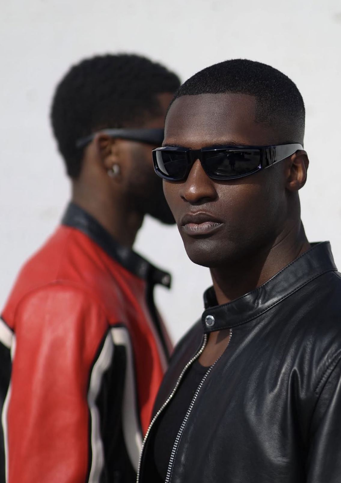 Two models in red and black leather biker jackets with wraparound shades
