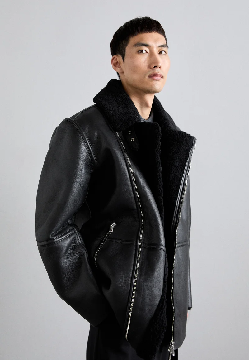 Model in black shearling-lined leather aviator jacket