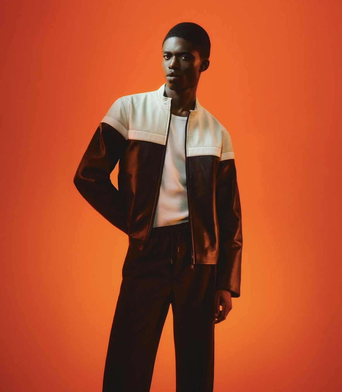 Two-tone leather colour-block jacket against a burnt-orange backdrop